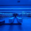 HLORENZO Los Angeles flagship by Oliviero Baldini, wide interior view under blue lighting with suspended wire-frame structures and central concrete counter