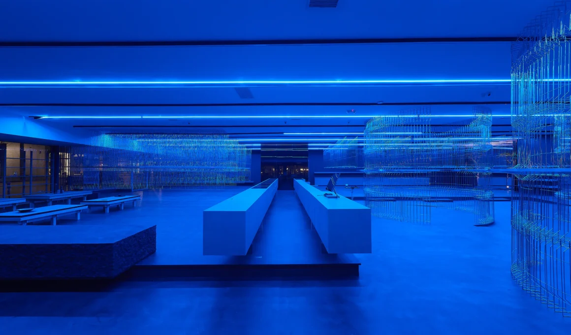 HLORENZO Los Angeles flagship by Oliviero Baldini, wide interior view under blue lighting with suspended wire-frame structures and central concrete counter