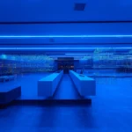 HLORENZO Los Angeles flagship by Oliviero Baldini, wide interior view under blue lighting with suspended wire-frame structures and central concrete counter