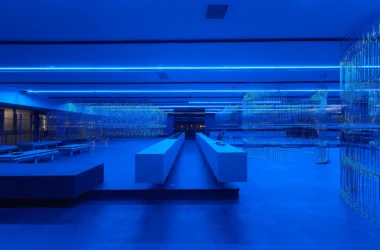 HLORENZO Los Angeles flagship by Oliviero Baldini, wide interior view under blue lighting with suspended wire-frame structures and central concrete counter