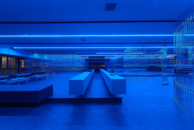 HLORENZO Los Angeles flagship by Oliviero Baldini, wide interior view under blue lighting with suspended wire-frame structures and central concrete counter