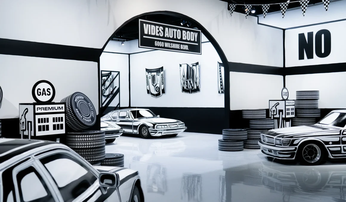 Joshua Vides Flat Out exhibition at Petersen Automotive Museum, Vides Auto Body archway, hand-painted vehicles and gas station props