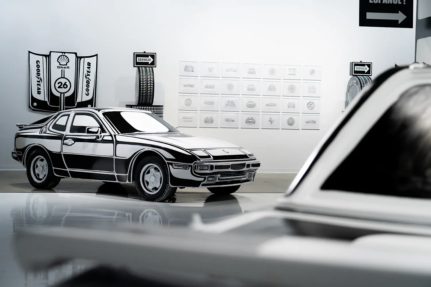 Hand-painted Porsche 944 at Joshua Vides Flat Out exhibition, Shell and Goodyear wall graphics, sketch grid backdrop
