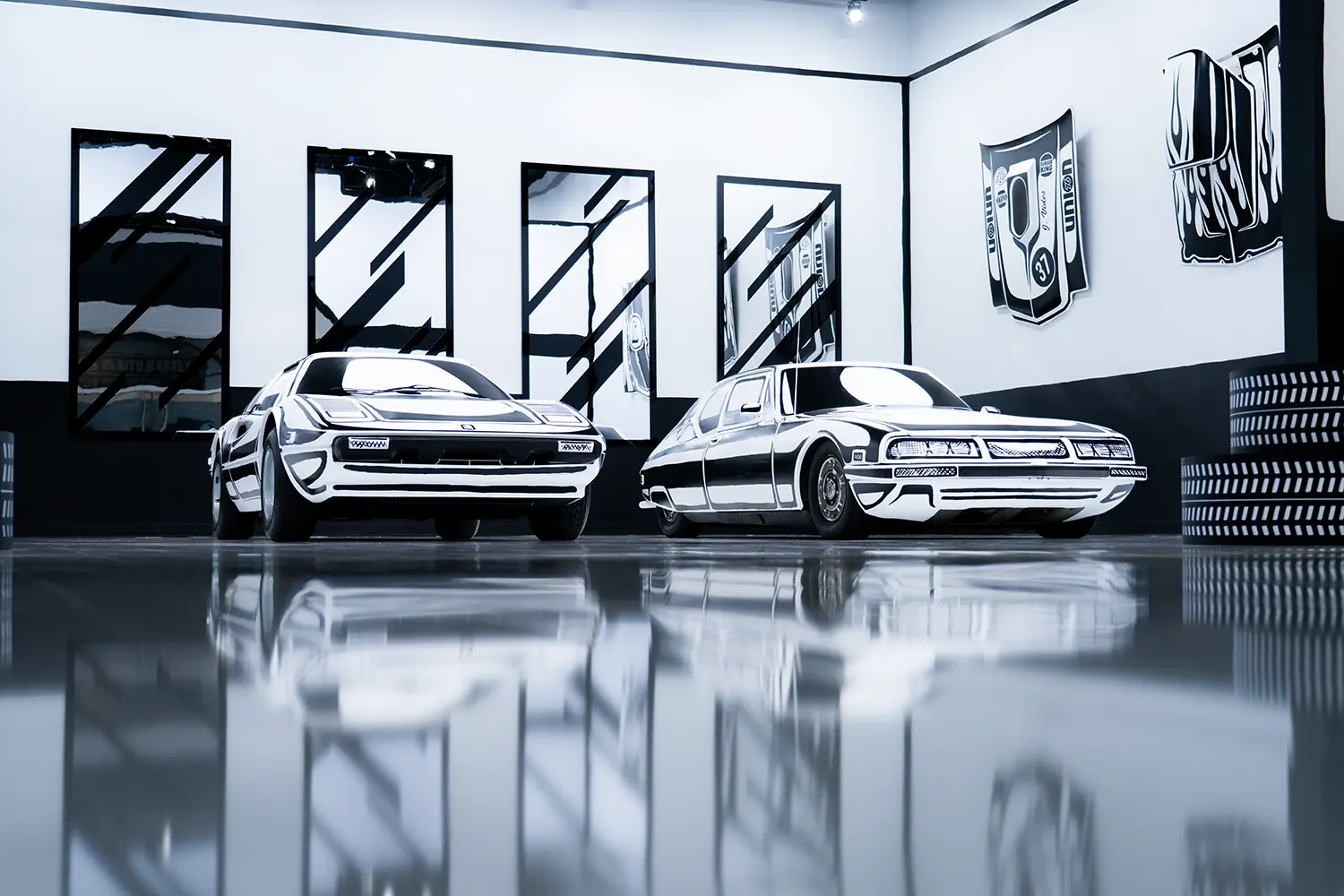 Two hand-painted vehicles at Joshua Vides Flat Out exhibition, angular wall graphics, reflective gallery floor