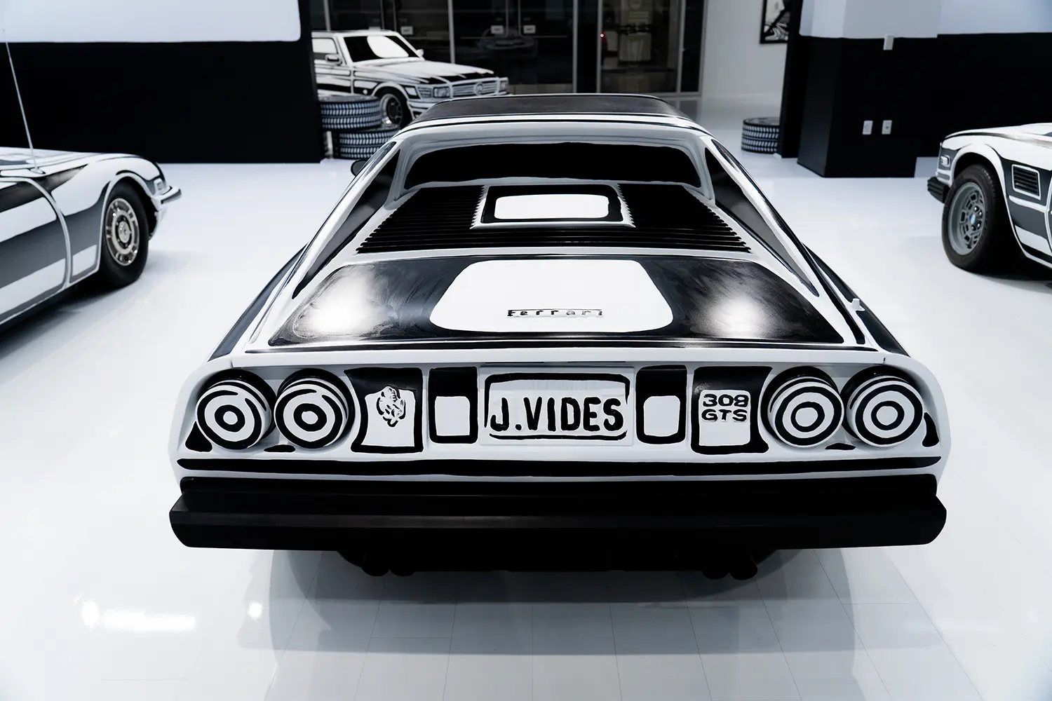 Rear view of hand-painted Ferrari 308 GTS at Joshua Vides Flat Out exhibition, J. Vides custom license plate