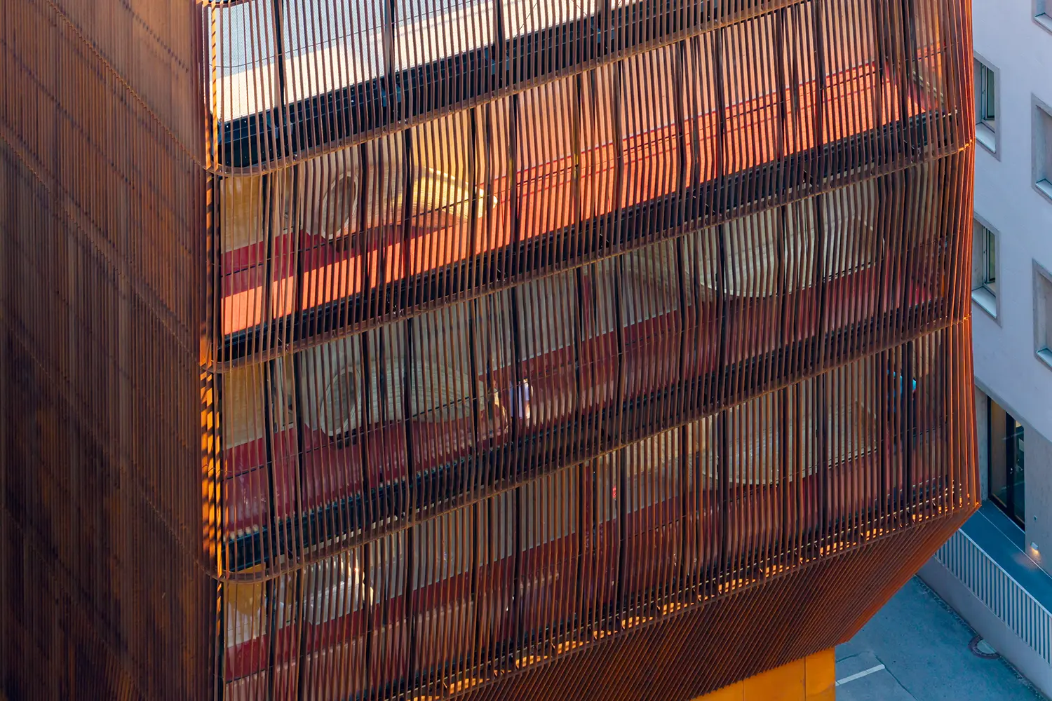Facade detail of the Kinderoase an der TUM by Kéré Architecture, vertical timber slats screening glimpses of colored interiors across four floors