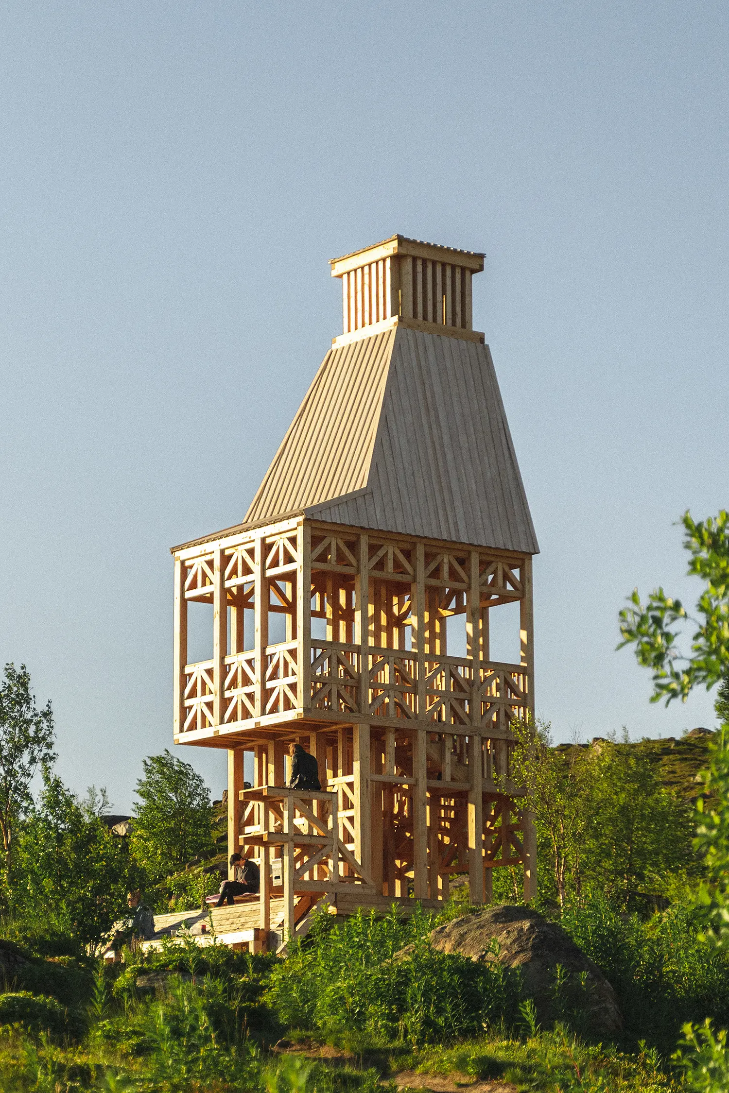 Kola Bay Lighthouse Viewpoint, full exterior view of the wood tower with visitors seated on the lower steps
