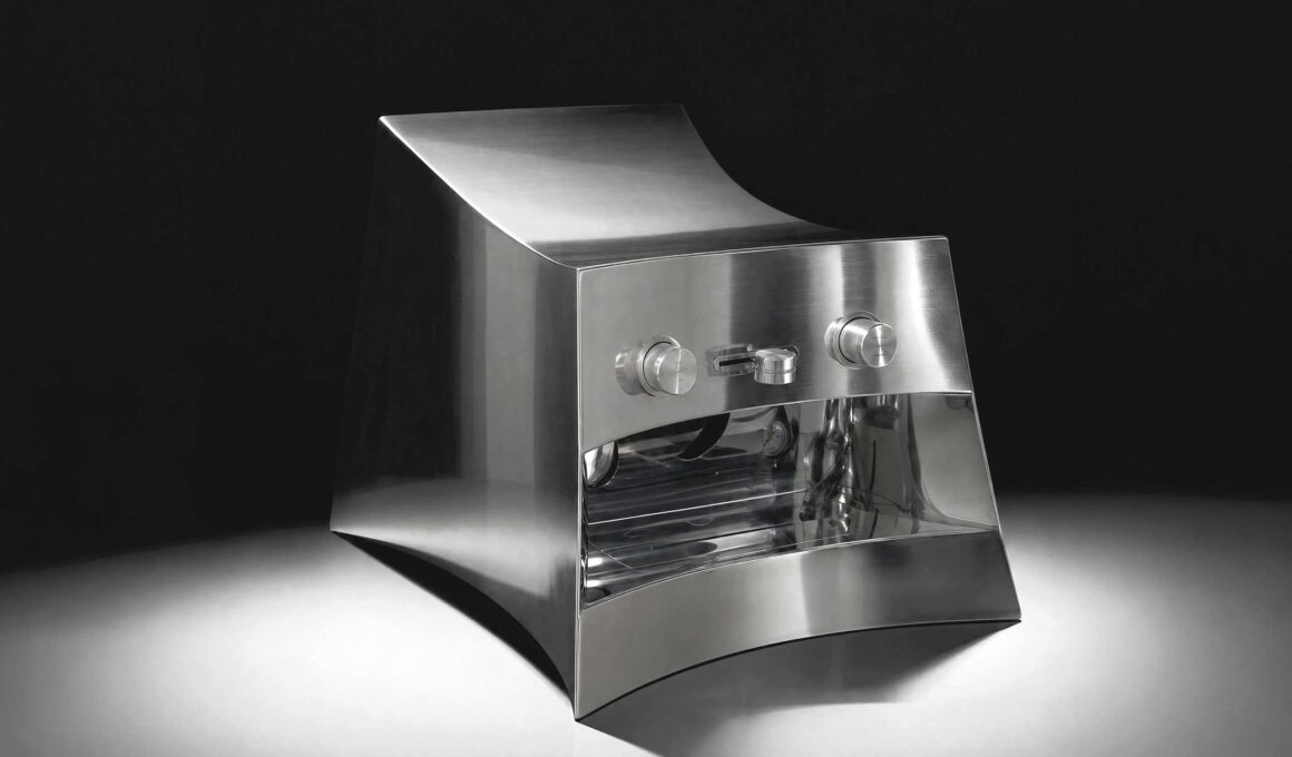 La Marzocco Linea Mini by CALIPER for Heliot Emil x Joe & The Juice, front three-quarter view, curved polished stainless steel housing, black studio background