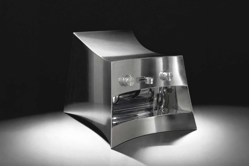 La Marzocco Linea Mini by CALIPER for Heliot Emil x Joe & The Juice, front three-quarter view, curved polished stainless steel housing, black studio background