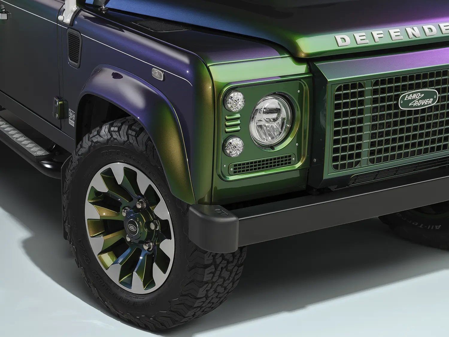 Detail of Land Rover Classic Defender V8 front corner, Spectral Green paint over grille and headlight, Sawtooth alloy wheel