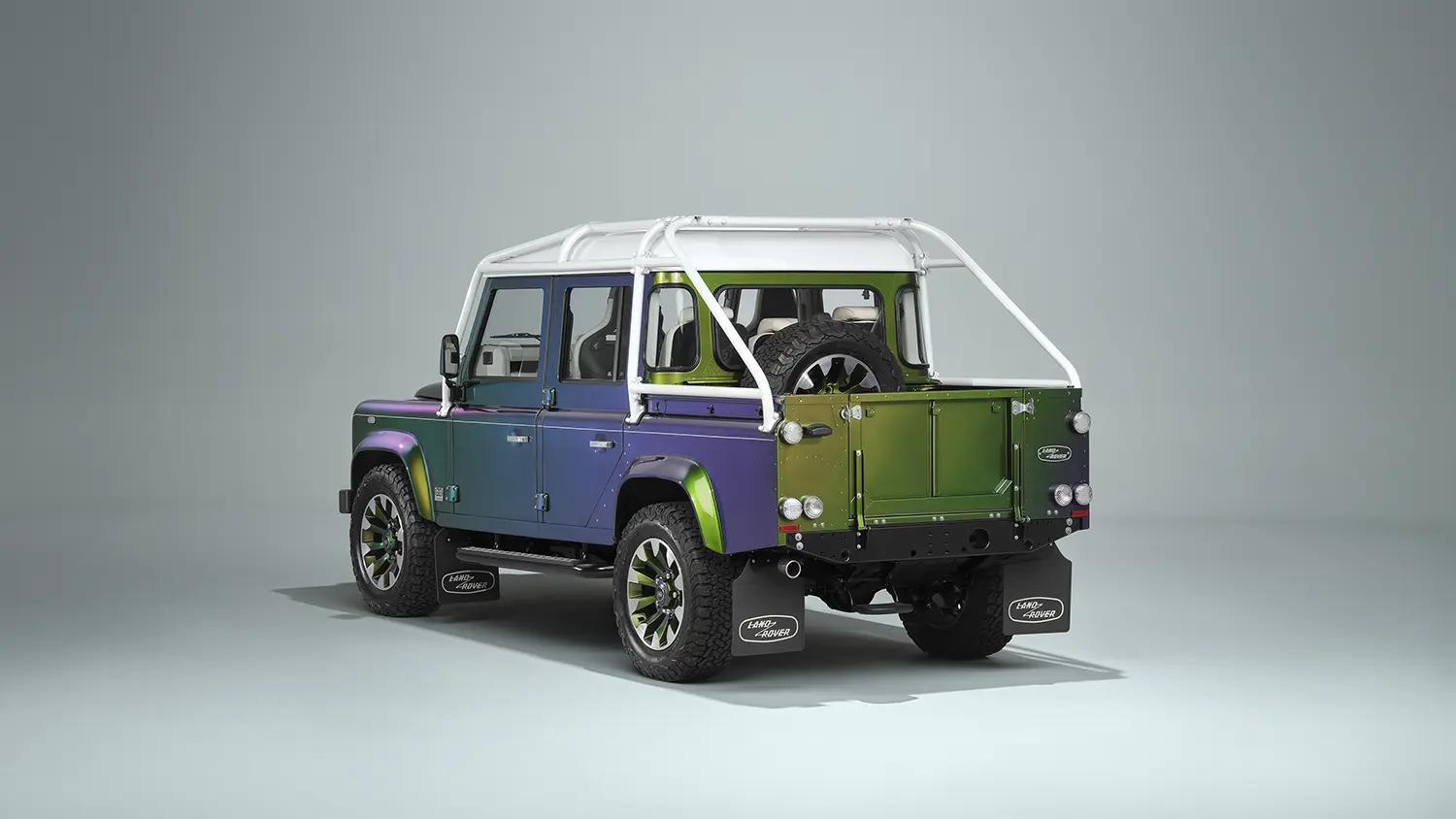 Land Rover Classic Defender V8 110 Double Cab Pick-Up, rear three-quarter view, Spectral Green to purple gradient, exposed spare wheel