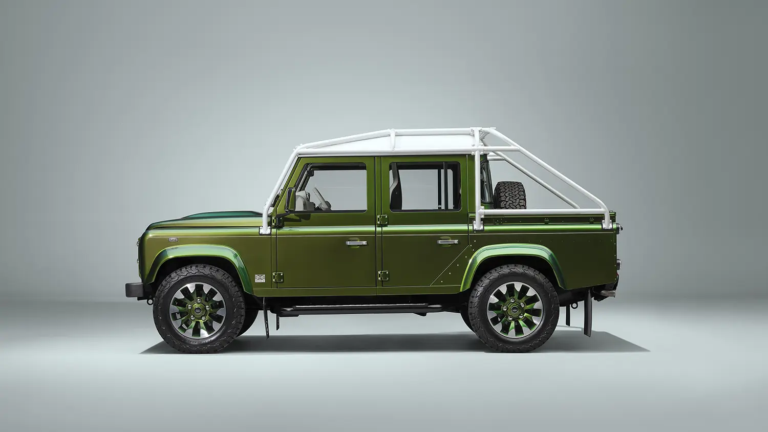 Land Rover Classic Defender V8 110 Double Cab Pick-Up, side profile, Spectral Green paint, white roll cage