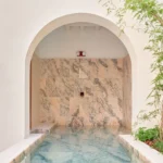 Casa Puerto marble-clad pool corridor arched threshold outdoor shower fixture peach marble wall