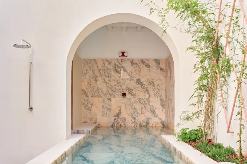 Casa Puerto marble-clad pool corridor arched threshold outdoor shower fixture peach marble wall