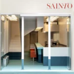 Sainto restaurant by Mur Mur, Paris — storefront view with teal-to-light floor gradient, staircase, and kitchen counter