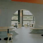 Eleventhfloor Restaurant by Noue Studio, Granges-Paccot — circular concrete cutout wall with wood benches and stools, neon signage