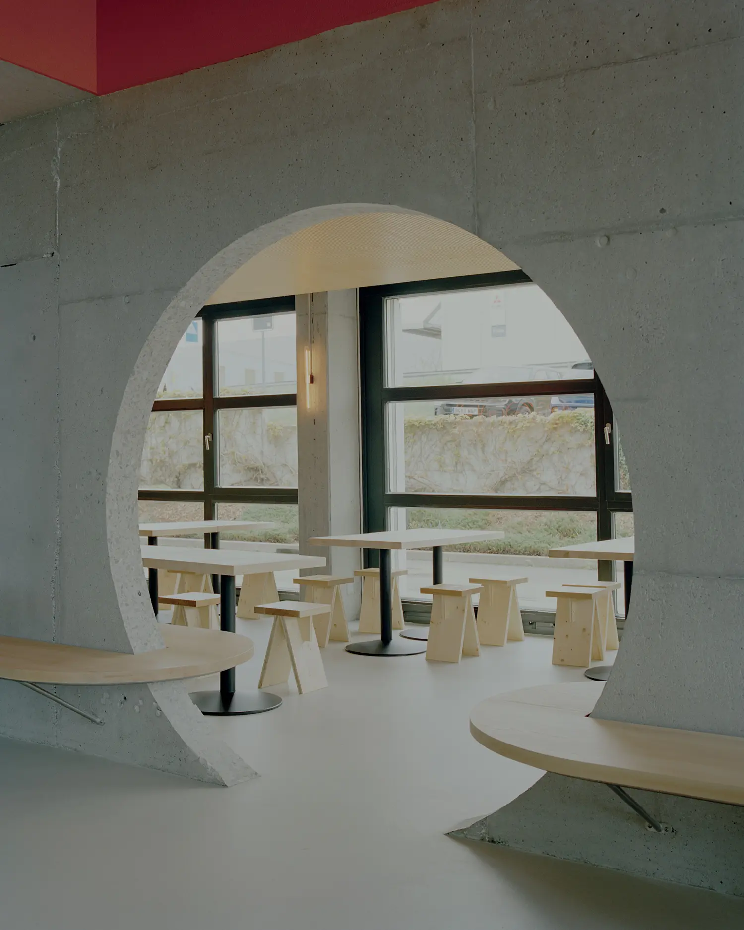 Eleventhfloor Restaurant by Noue Studio, close-up of circular concrete opening framing window and seating beyond