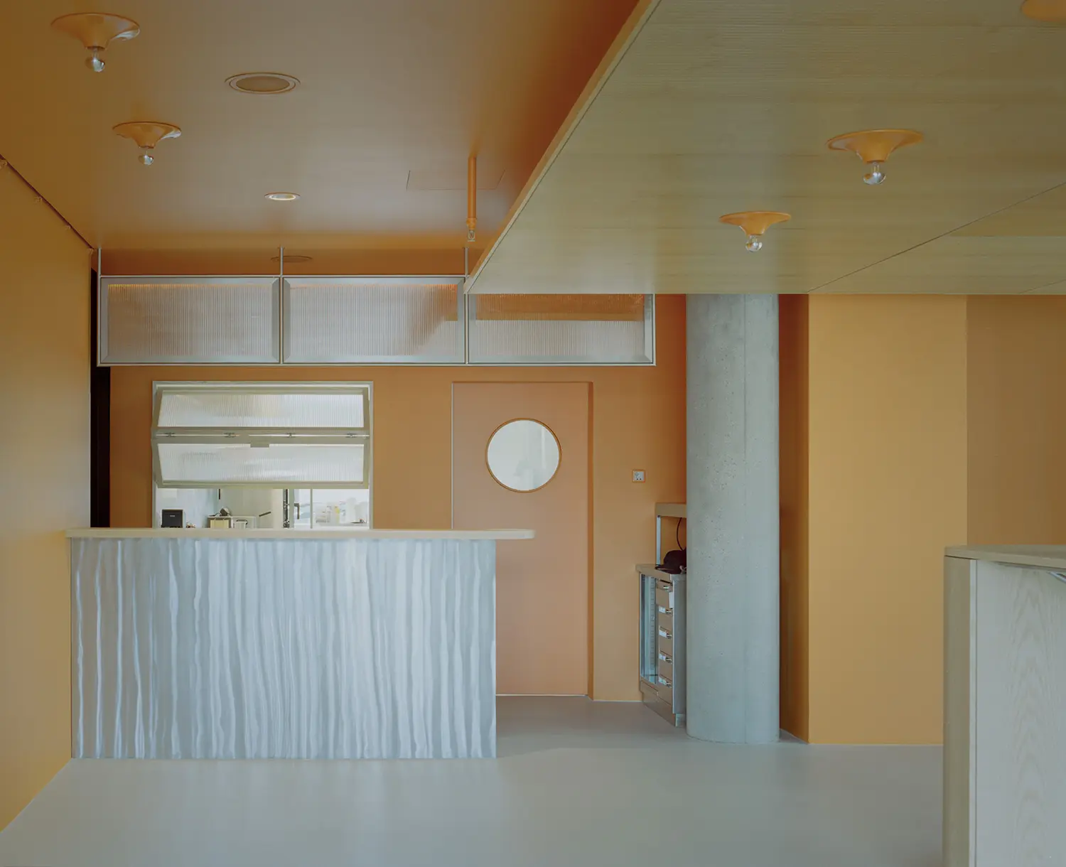 Eleventhfloor Restaurant by Noue Studio, bar counter in fluted textured panel against orange-lacquered wall and concrete column