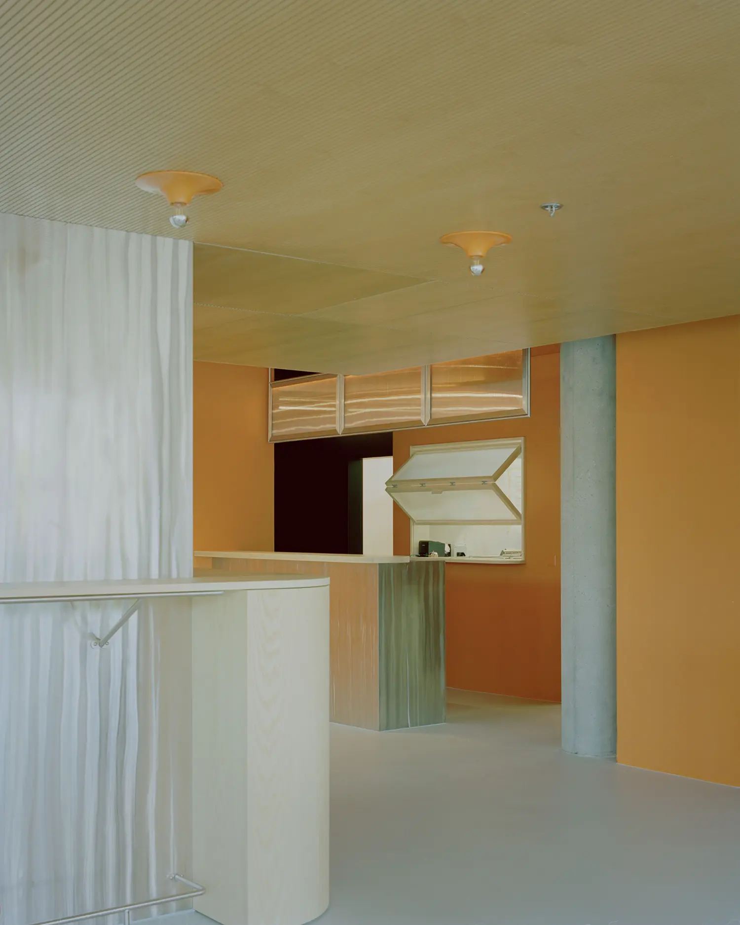 Eleventhfloor Restaurant by Noue Studio, service counter with fluted wood cladding against orange walls and concrete column