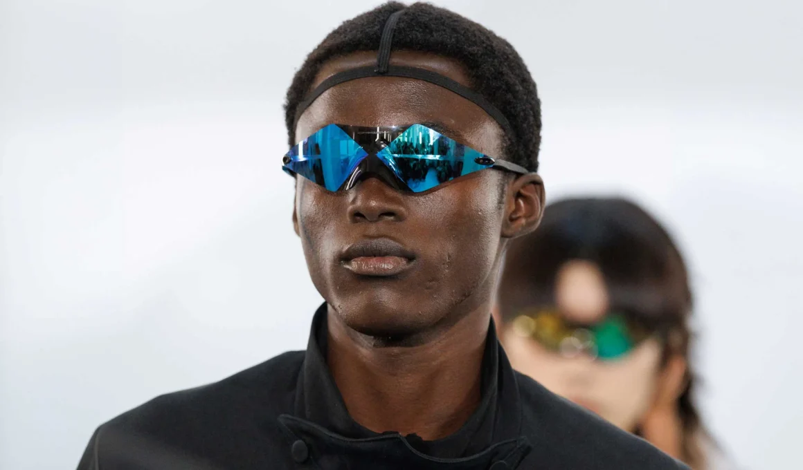 Model wearing Oakley wrapped-lens prototype eyewear in blue mirrored colorway backstage at Paris Fashion Week