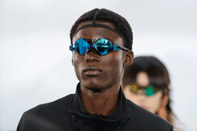 Model wearing Oakley wrapped-lens prototype eyewear in blue mirrored colorway backstage at Paris Fashion Week