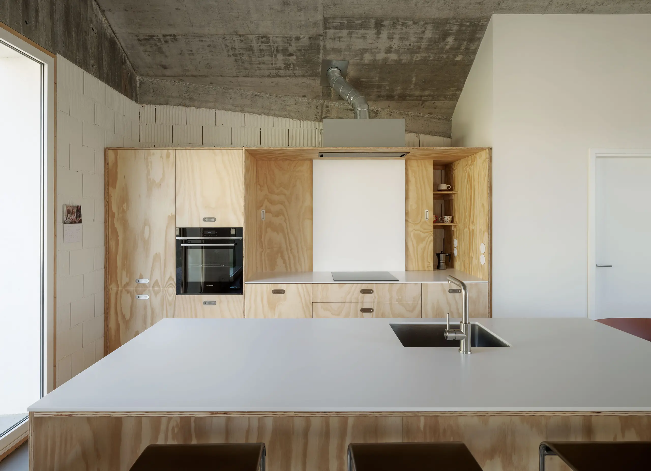 Cecebre House by Sinaldaba, Galicia, kitchen fully clad in pine plywood cabinetry, integrated oven, exposed concrete ceiling