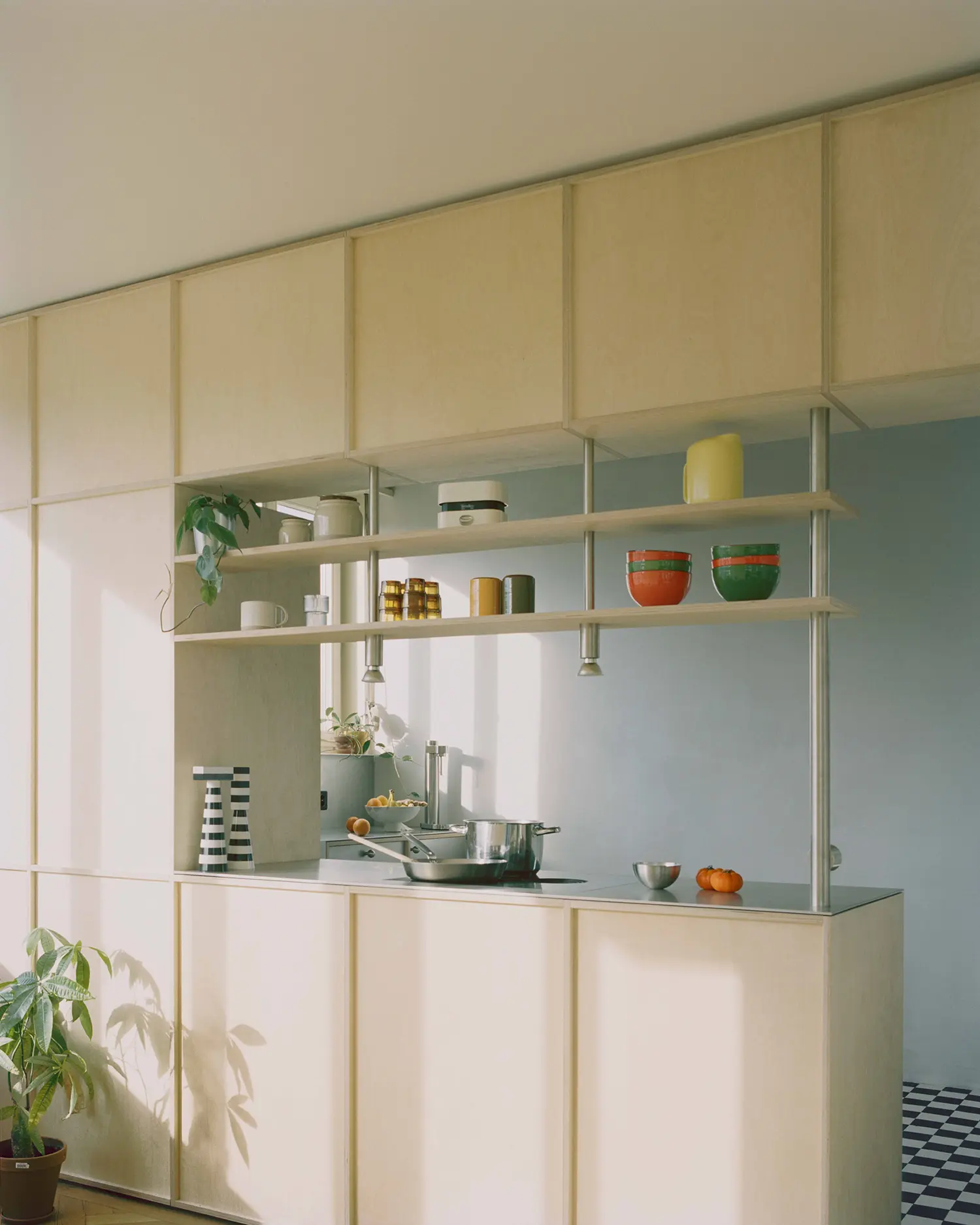 Noue Studio kitchen, Fribourg, birch plywood open shelving with ceramic bowls and glass jars, blue wall visible beyond