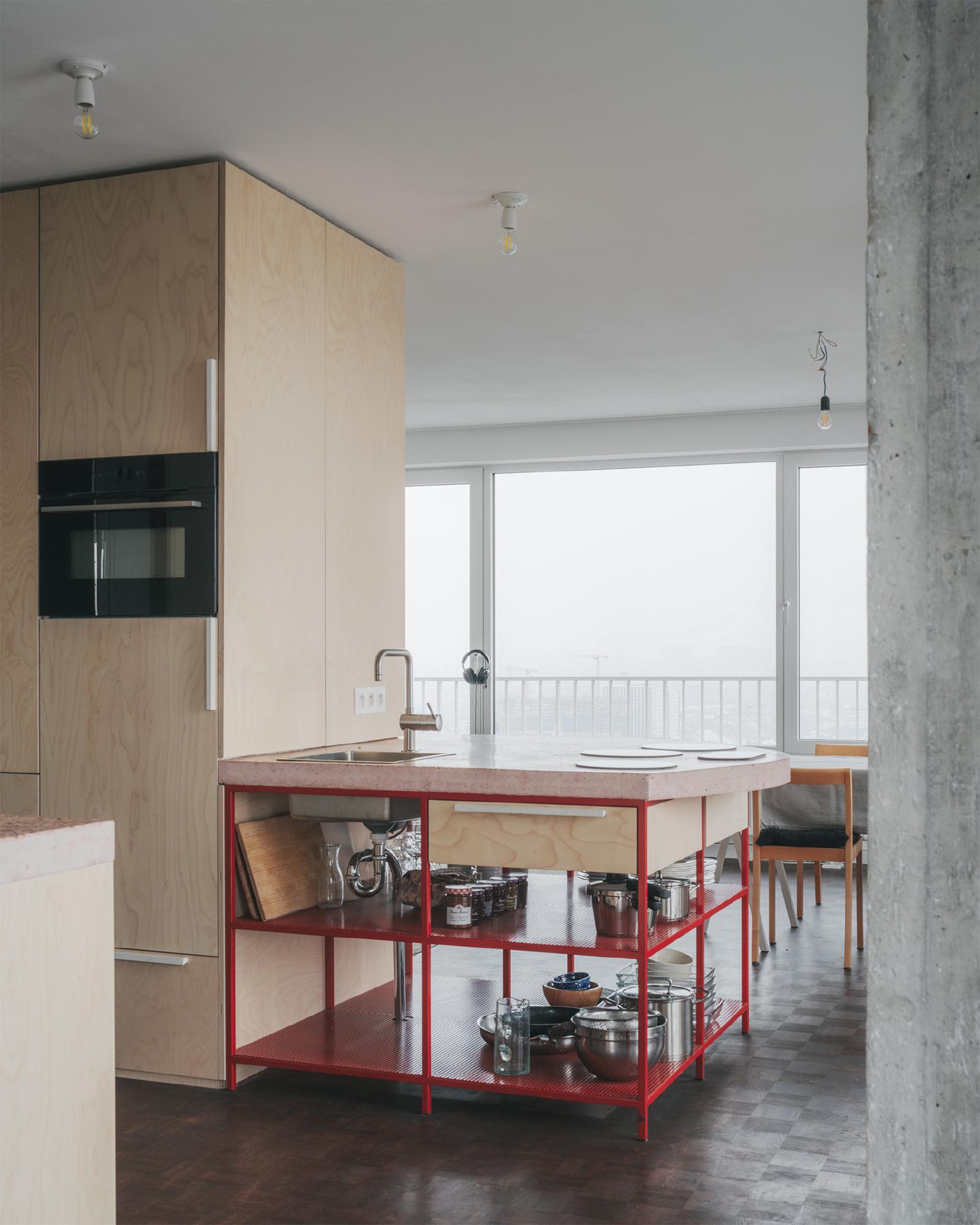 Altstadt apartment, Brussels, kitchen volume in plywood and red steel frame, concrete countertop, city skyline through window
