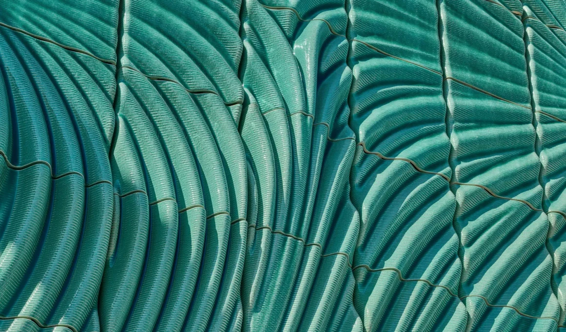 Detail of Powerwall by Studio RAP showing ribbed 3D-printed ceramic tiles in translucent turquoise glaze with radiating relief pattern