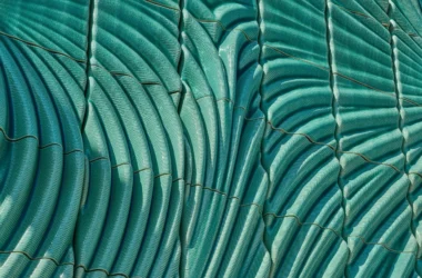 Detail of Powerwall by Studio RAP showing ribbed 3D-printed ceramic tiles in translucent turquoise glaze with radiating relief pattern