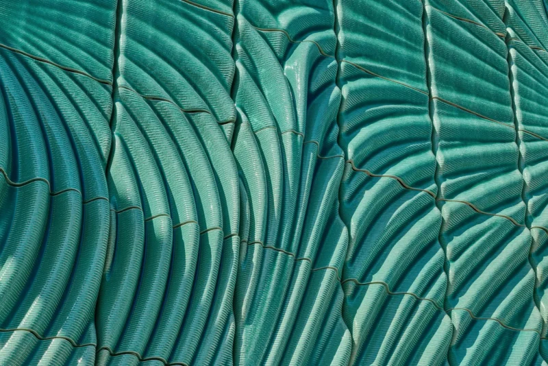 Detail of Powerwall by Studio RAP showing ribbed 3D-printed ceramic tiles in translucent turquoise glaze with radiating relief pattern