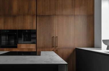 High-spec kitchen with walnut cabinetry, built-in oven, coffee machine, and stone island showing integrated appliance planning