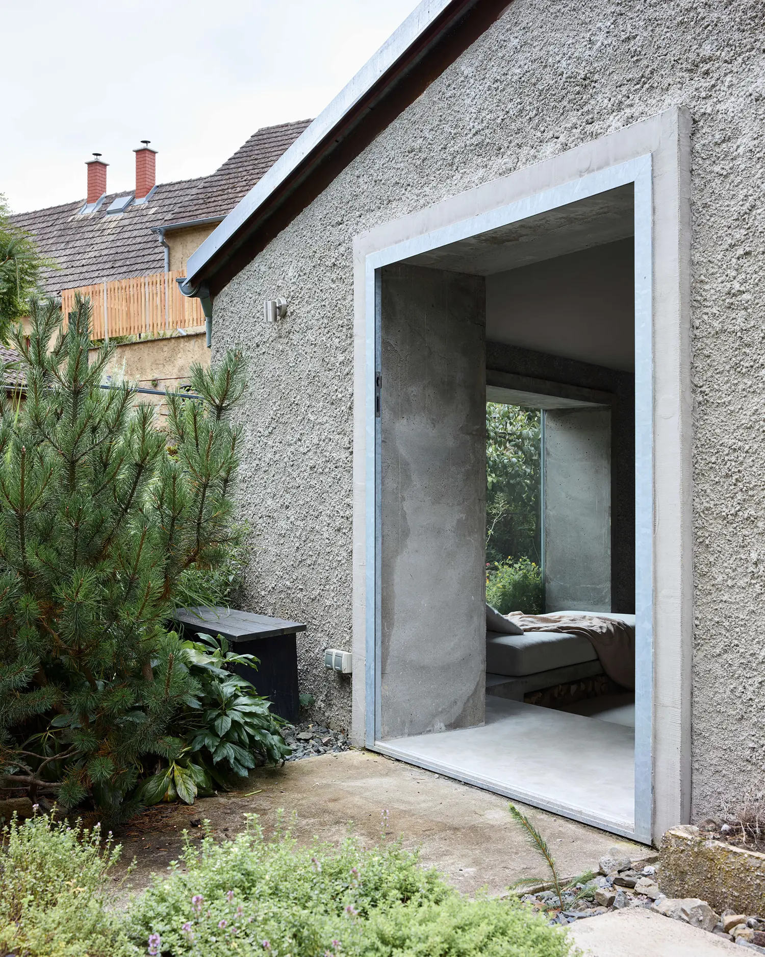 Panoší Újezd Summer House by Lenka Milerová: monolithic concrete door frame cut into the rendered exterior wall, opening onto the concrete window bench inside