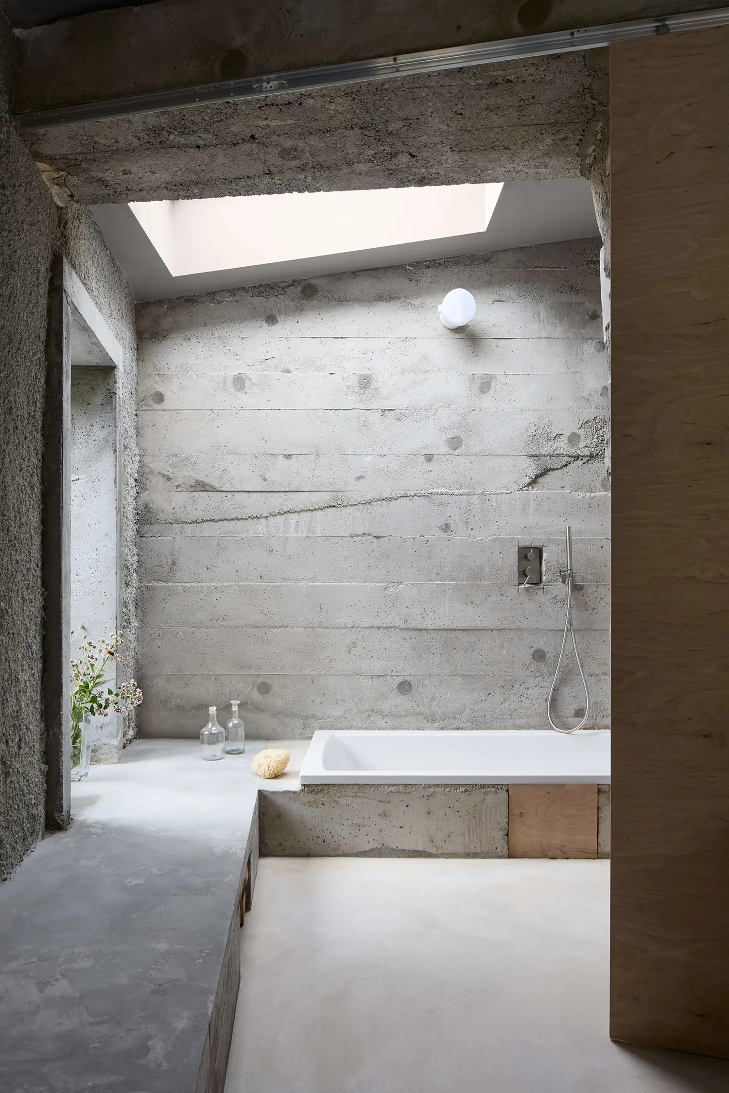 Panoší Újezd Summer House by Lenka Milerová: board-formed concrete bathroom with built-in bathtub, skylight, and exposed steel shower fixture