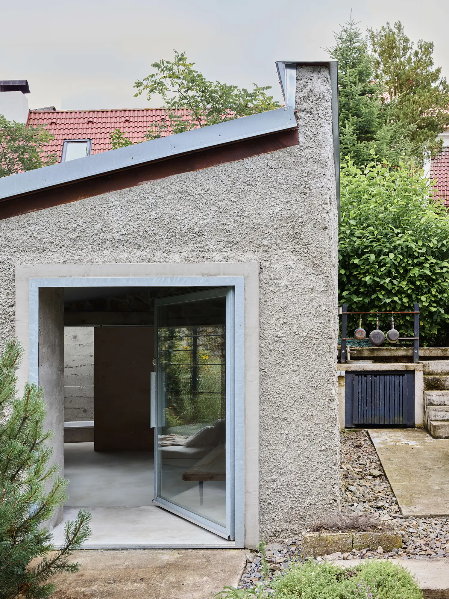 Panoší Újezd Summer House by Lenka Milerová: exterior gable end with door open to the interior daybed, outdoor kitchen visible alongside with hanging pots