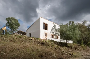 White single-family house on a hillside under a stormy sky, with solar panel structure visible nearby