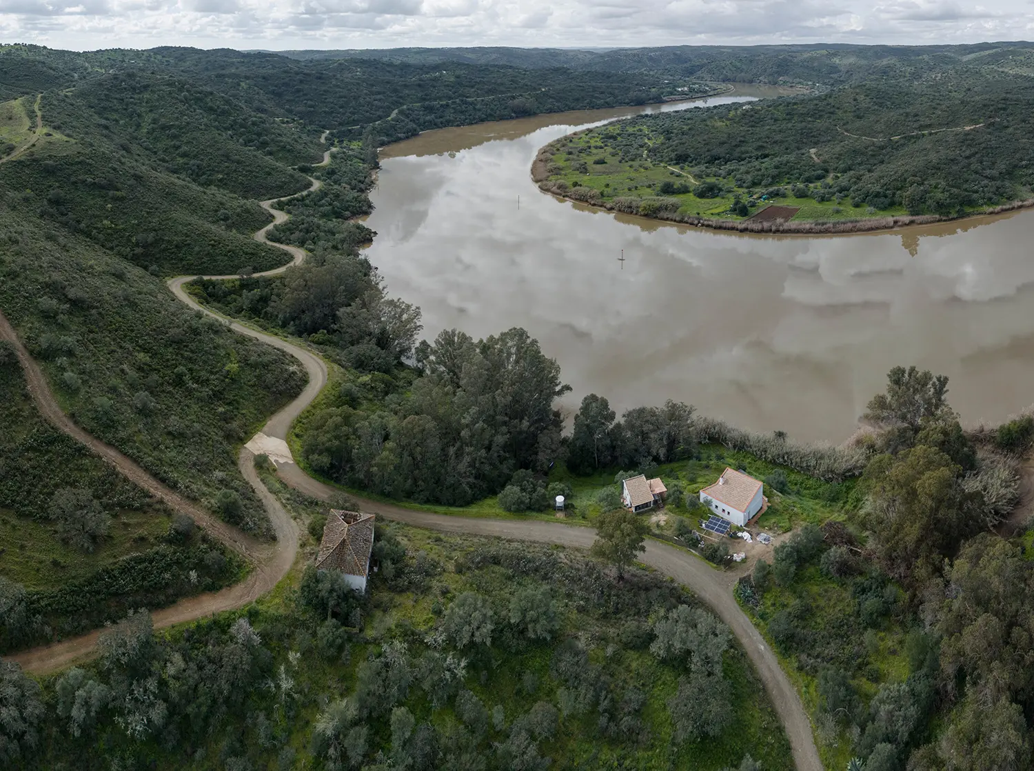 Aerial view of Stone and Water house on a bend of the Guadiana River with photovoltaic panels visible nearby