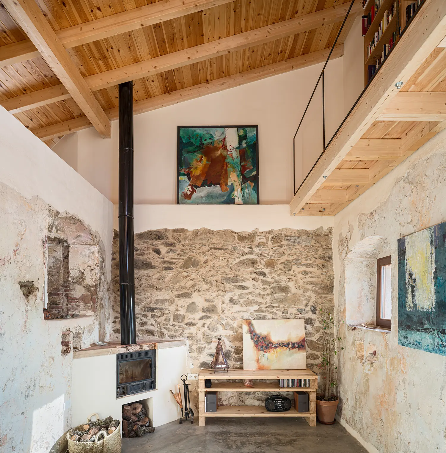 Living room corner with reused stone chimney and exposed original masonry inside Stone and Water house