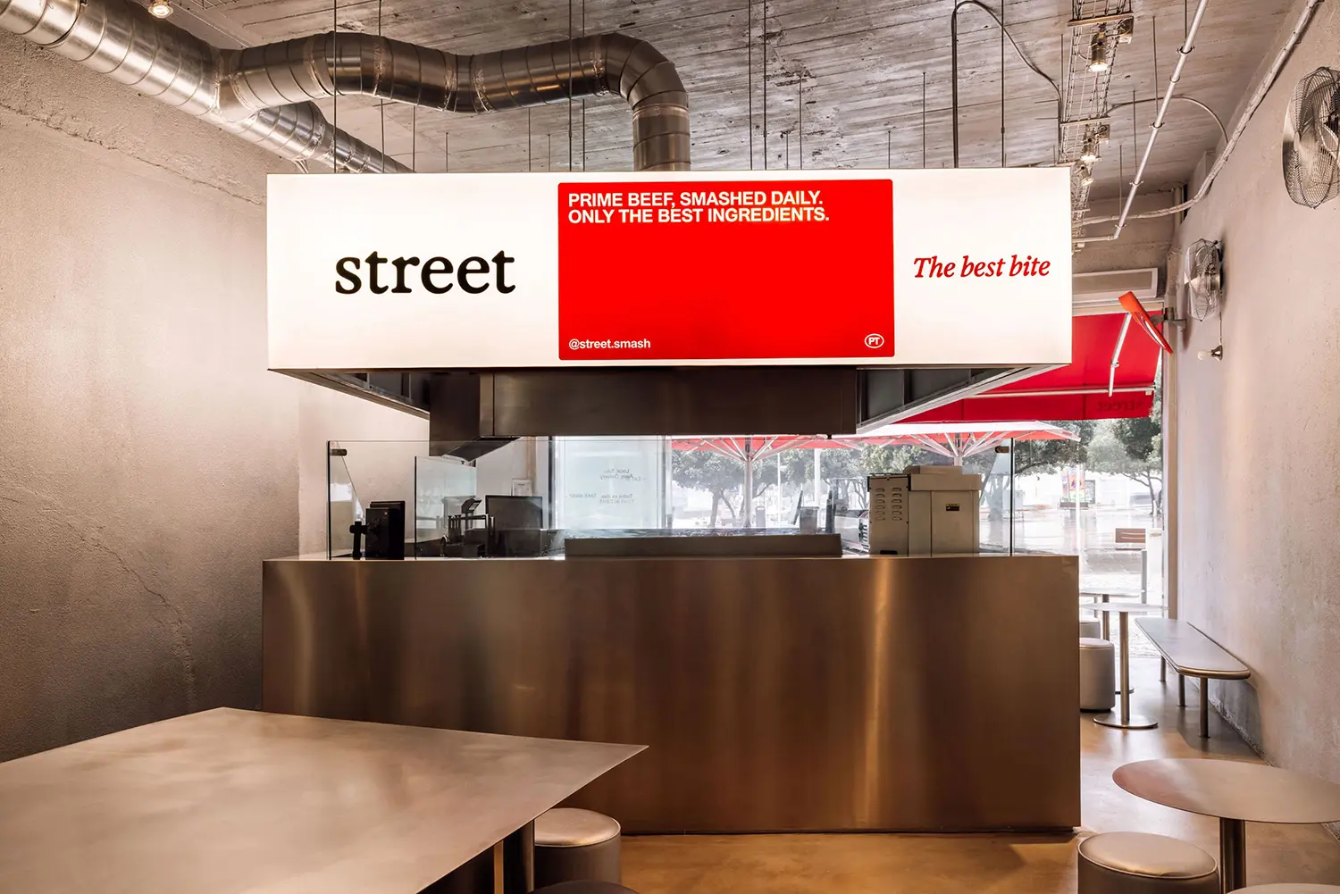 Close view of the illuminated light box and stainless steel kiosk counter at Street Smash Burgers by XXXI.studio, Almada