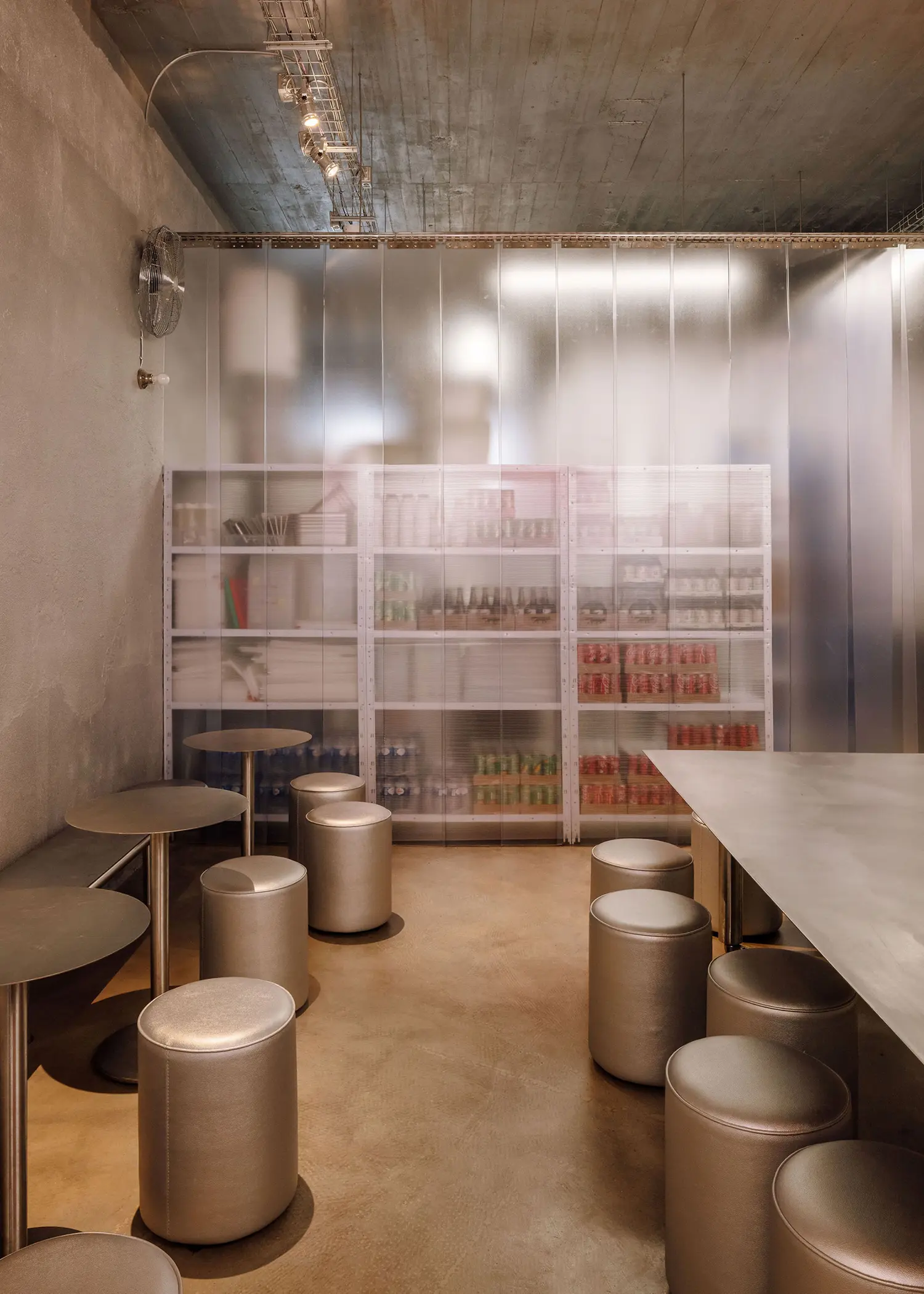 Translucent polycarbonate storage wall and stainless steel stools in the back dining area of Street Smash Burgers by XXXI.studio