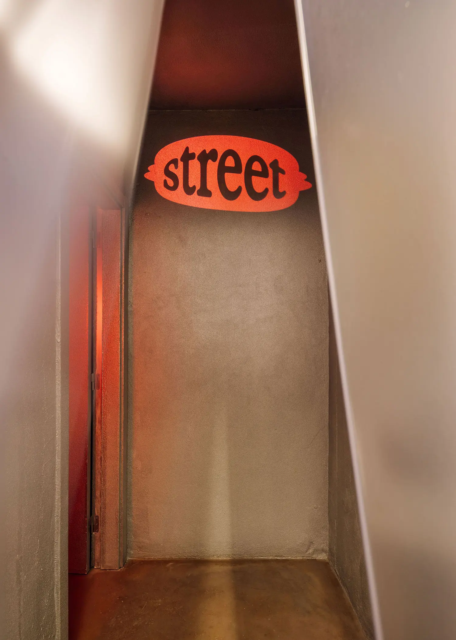 Illuminated red "street" sign inside a narrow concrete alcove at Street Smash Burgers by XXXI.studio, Almada