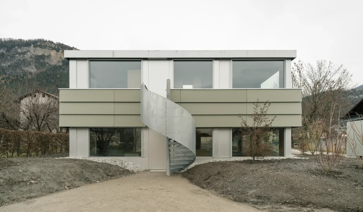 Caloz Bramois House by R2A architectes, Switzerland, exterior facade with spiral staircase and sunken ground floor. Photo: Dylan Perrenoud