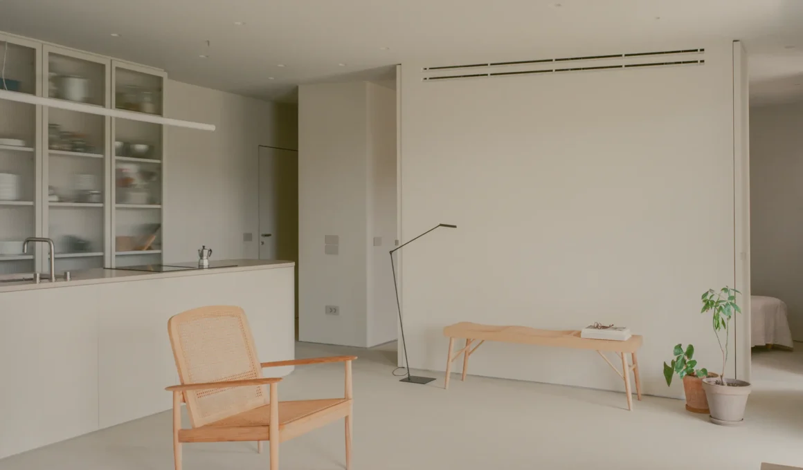 Kifisia Apartment by Georgios Apostolopoulos Architects, open living and kitchen area with cane lounge chair and microcement flooring
