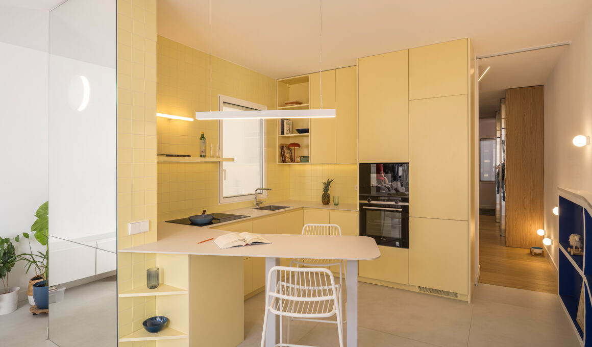 Casa JAM by gon architects, Madrid: mirrored wall beside yellow ceramic-tiled kitchen and blue steel beam. Photo: Imagen Subliminal