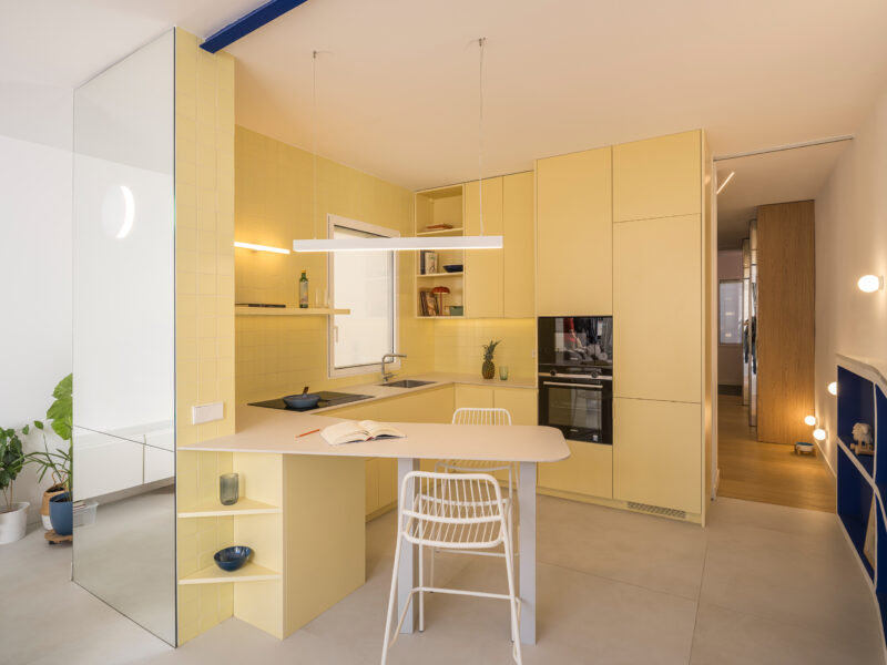 Casa JAM by gon architects, Madrid: mirrored wall beside yellow ceramic-tiled kitchen and blue steel beam. Photo: Imagen Subliminal