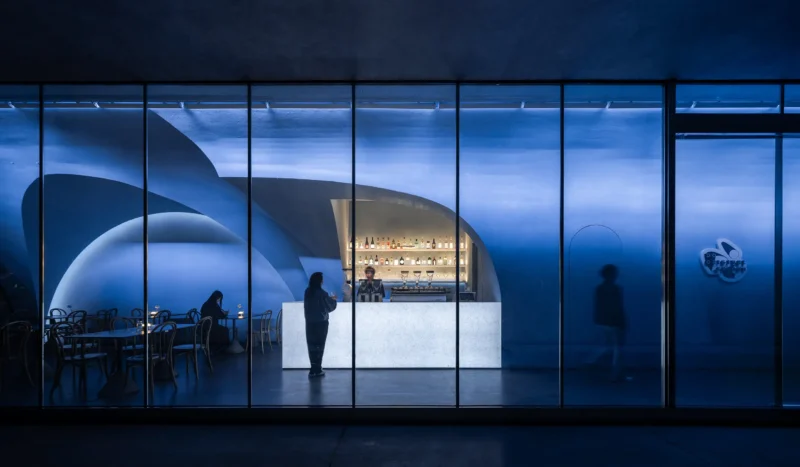 Luminous Tunnel DOS Restaurant by MARS Studio glass facade at night with glowing white bar counter, photo by Luo Canhui