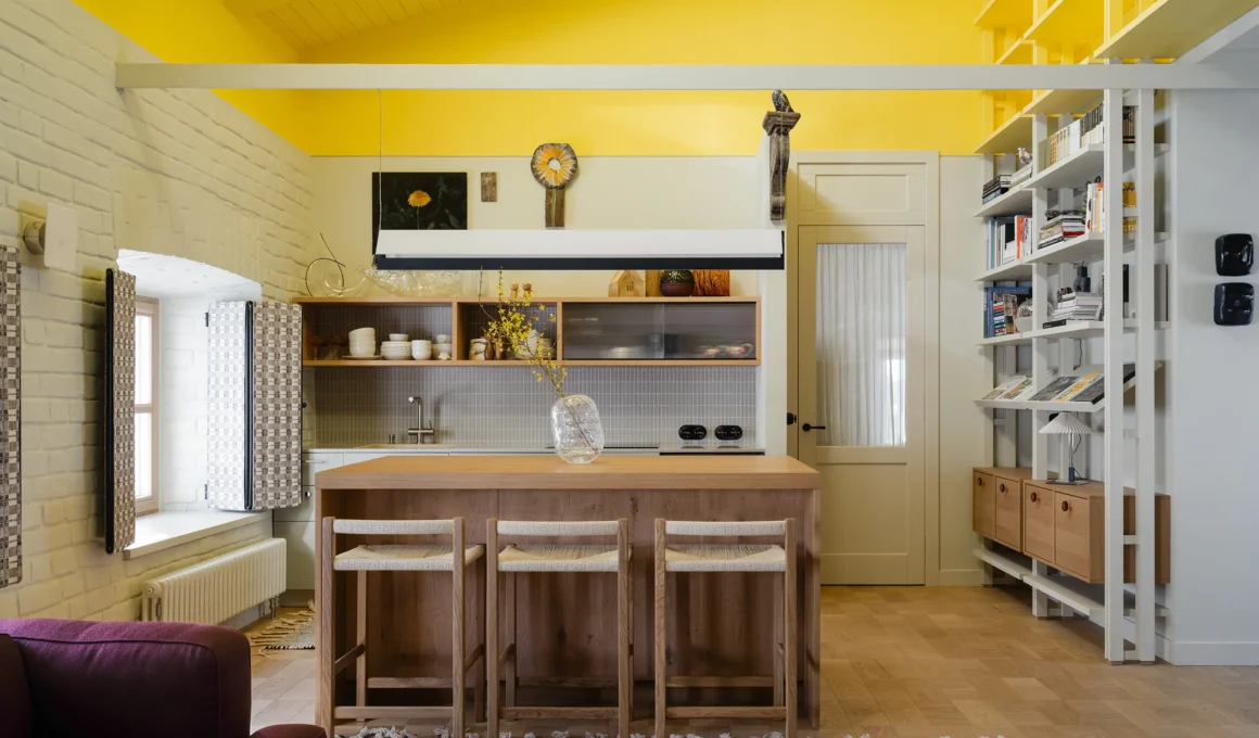 Mimosa Apartment by Treivas, with a lemon yellow ceiling above beige walls, painted brickwork and an oak kitchen island | Photo Varvara Toplennikova