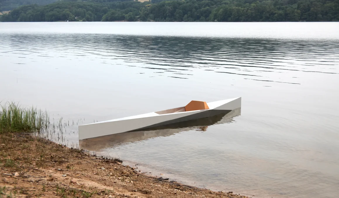 Sharp kayak by Guillaume Bloget, its folded aluminum hull resting at the water's edge of a lake in the Morvan, with a cork seat in the cockpit | Images courtesy of Guillaume Bloget