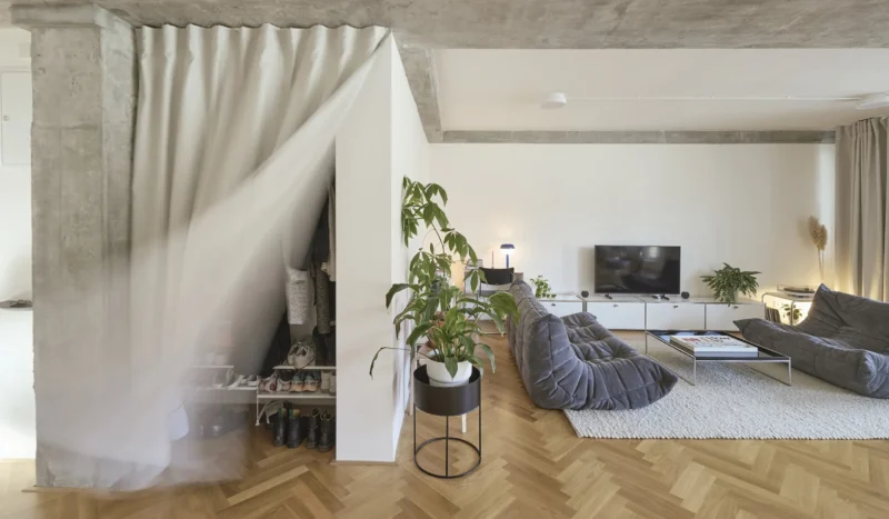 RDTH architekti's No-Wall Apartment in Prague, concrete beam ceiling, herringbone floor, curtain-enclosed storage. Photo by Filip Beránek.