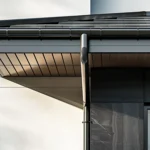 Aluminium guttering integrated into a dark modern facade with concealed downpipe